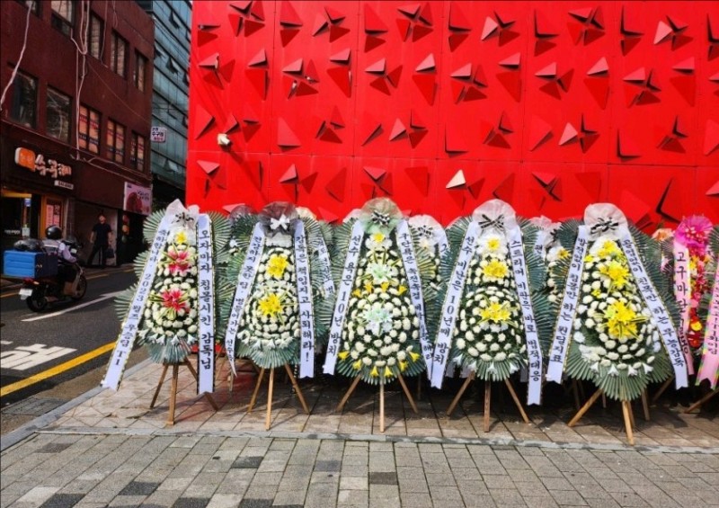 T1大楼今日又多了许多白色花圈,盖住了昨日有寓意祝福的粉色花圈
